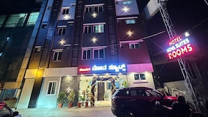 A multi-story hotel building with a sign for 'Hotel Nova Suites' and a neon sign indicating 'Hotel Rooms'. - Hotel Nova Suites, Bellandur Gate, Sarjapur Road (Bengaluru)