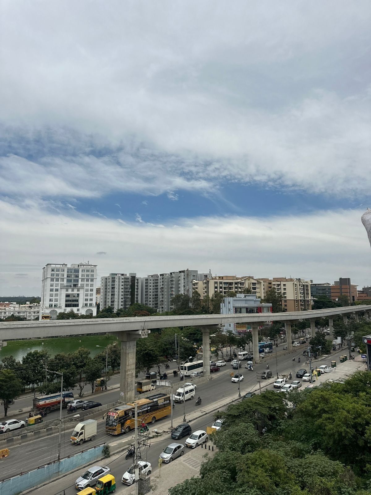A busy urban street with a multi-level overpass, various vehicles, and high-rise buildings in the background.