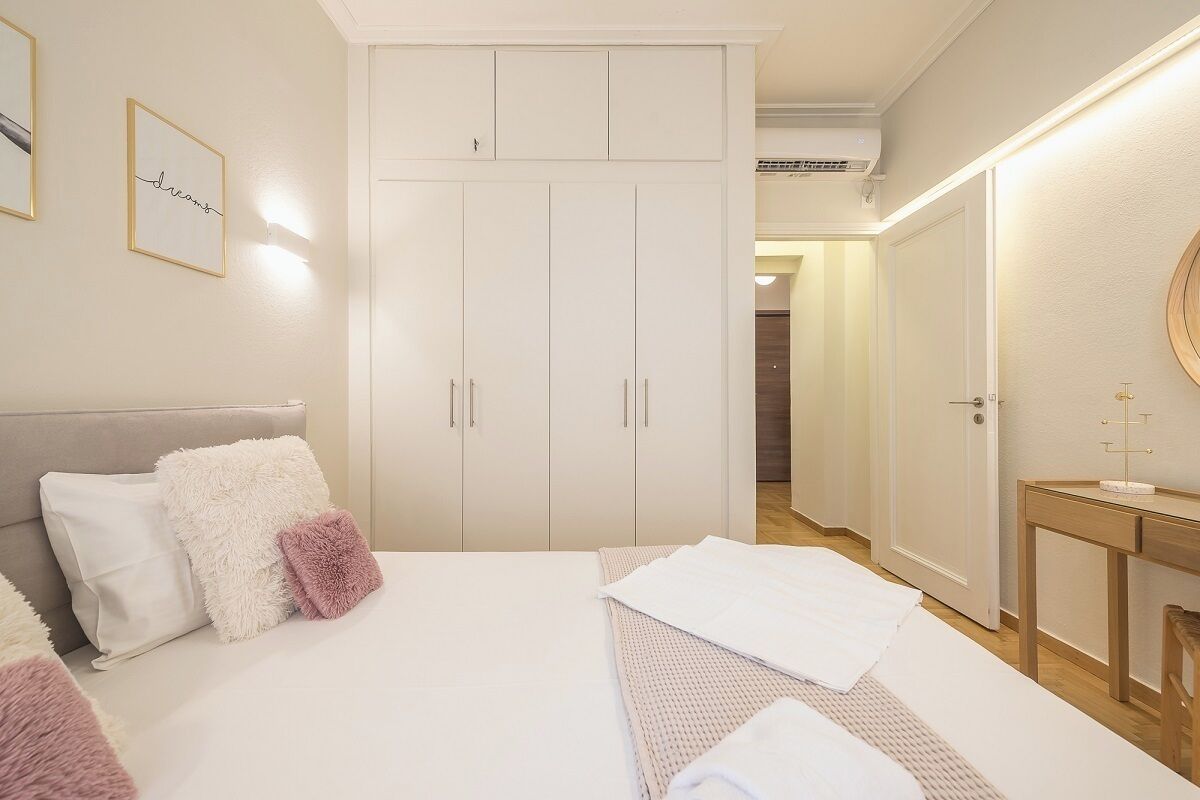 A bedroom with a bed, a wardrobe, a bedside table, and a mirror.