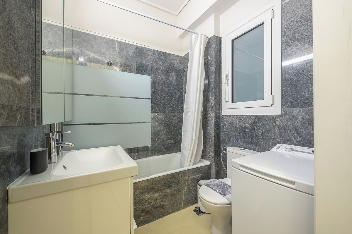 Een moderne badkamer met een wit wastafel, een spiegel, een badkuip en een toilet.