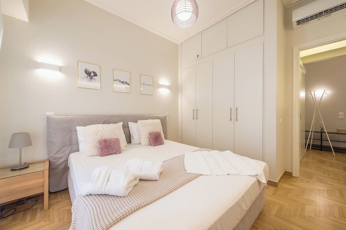 A neatly arranged bedroom with a large bed, bedside tables, and a wardrobe.