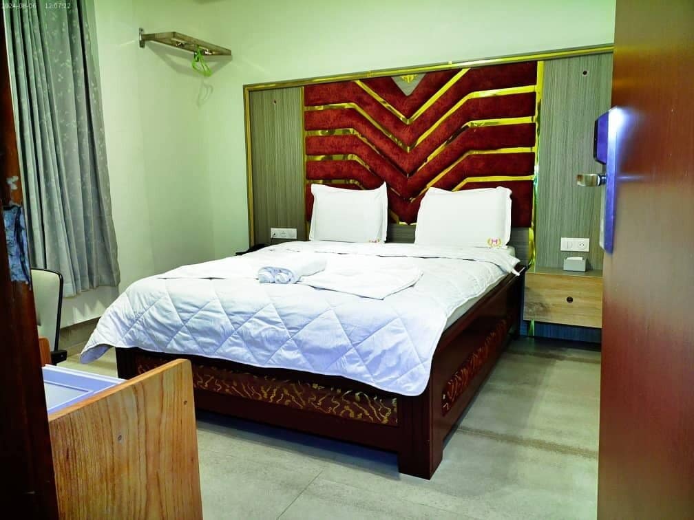 Une chambre d’hôtel avec un grand lit, une tête de lit en bois et une table de chevet.