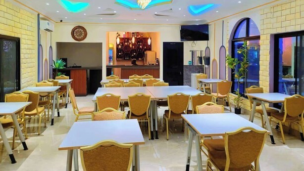 A dining area with tables and chairs, a bar area, and a chandelier. - Hotel Santa Bella (Douala)