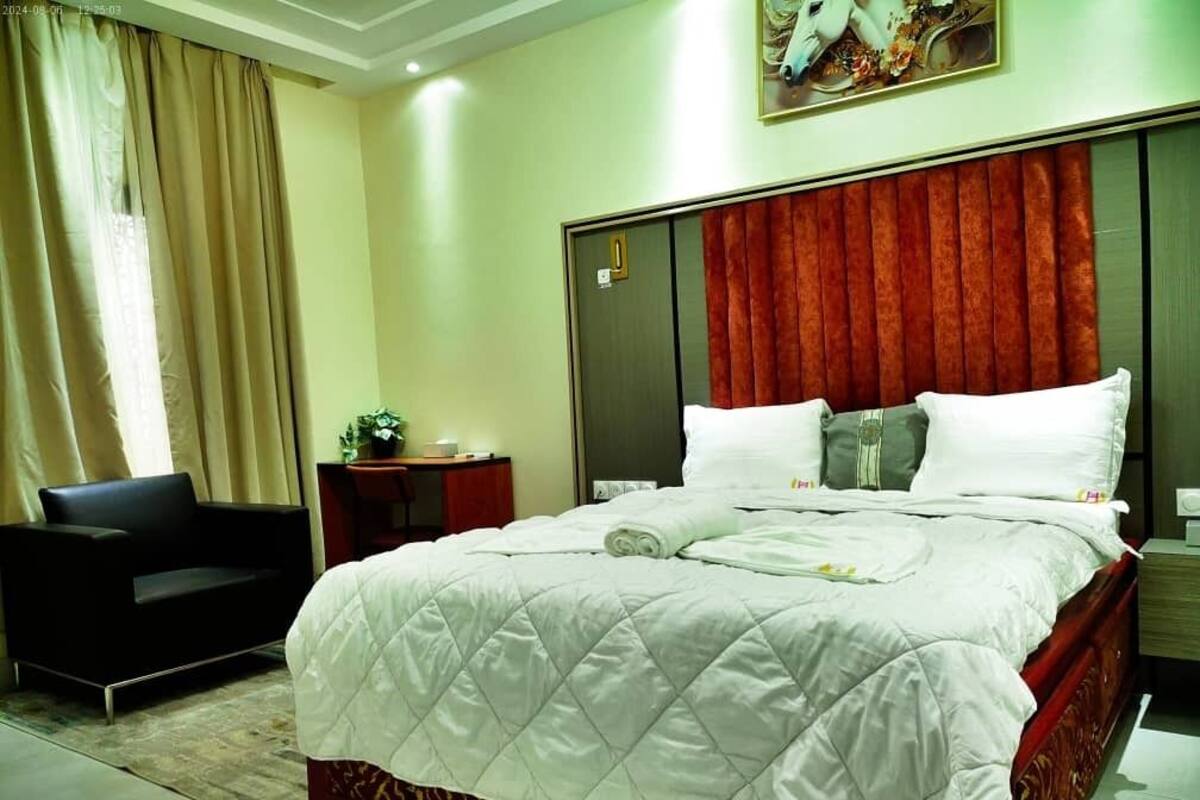 Une chambre d’hôtel avec un grand lit, un bureau, une chaise et un tableau au mur.