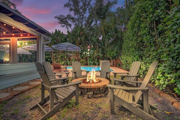 A patio with a fire pit, outdoor seating, and a pool.