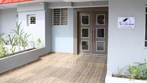 A hotel entrance with a wooden floor, a red awning, and a sign for 'The Cafe House by Cafe and Cater Limited'. - The Cate House Hotel (Lagos)