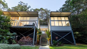 Een modern huis met twee verdiepingen, een overdekte oprit, een trap naar de ingang en een verzorgd gazon.