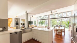 Een moderne keuken met witte kasten, een vaatwasser, en een eethoek met een houten tafel en stoelen.