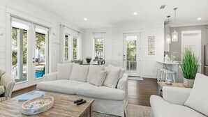 A spacious living room with a large sofa, a coffee table, and a dining area with chairs and a table. - NEW! 4 BR with en-suite baths, HEATED Pool, Bikes, Gated Community, close to shopping & beach (Seagrove Beach)