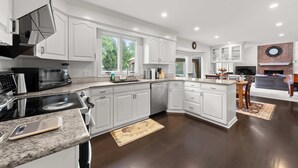 A modern kitchen with white cabinetry, a built-in microwave, and a large island. - The Gahanna Grand (Columbus)