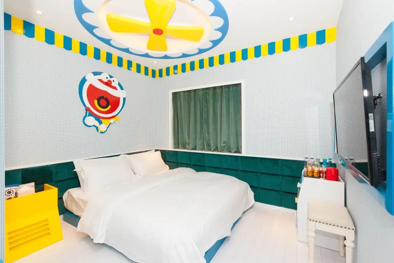A bedroom with a bed, a ceiling fan, a window with curtains, and a small table with bottles.
