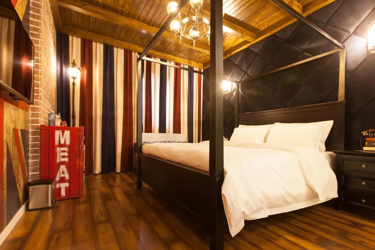 A four-poster bed with white linens, a red cabinet labeled "MEAT," and a chandelier.