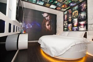 A modern bedroom with a large bed, a unique curved bedside table, and a wall decorated with movie posters. - Love Home Theme Concept Hotel (Xining)
