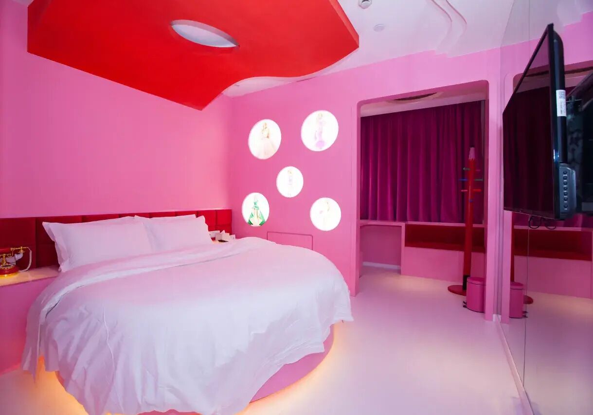 A pink-themed bedroom with a bed, a TV, and circular wall decorations.