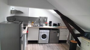 Eine kleine Küche mit Waschmaschine, Kaffeemaschine und Spüle.