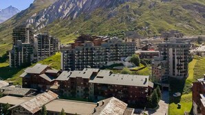 Un quartier résidentiel composé d’immeubles à plusieurs étages, dont certains sont dotés de balcons, avec une chaîne de montagnes en arrière-plan.