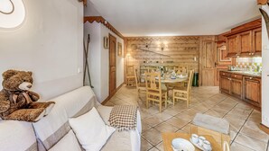 Un salon chaleureux avec un canapé, un ours en peluche et un coin repas doté de meubles en bois.
