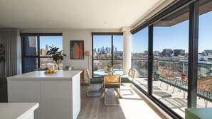 A modern apartment with a kitchen, dining area, and large balcony with city views.