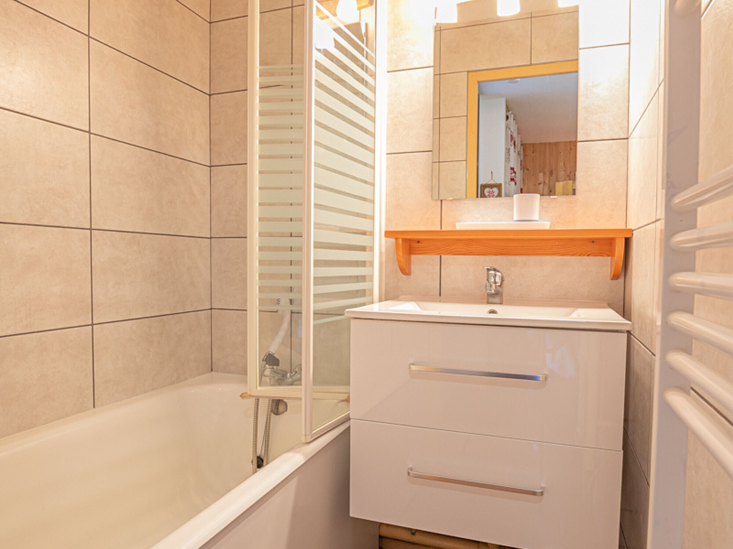 A bathroom with a bathtub, a sink with a mirror above it, and a towel rack.