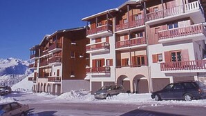 Un hôtel à plusieurs étages doté de balcons, d’un parking et entouré d’un paysage enneigé.