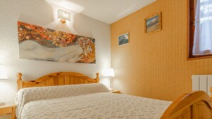 Une chambre à coucher avec un lit en bois, une table de chevet, une lampe fixée au mur et un tableau.