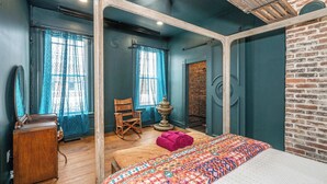 A room with a bed, a wooden dresser, a rocking chair, and a brick wall. - Timeless on Main 2 For 2 (Blanchester)