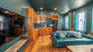 A modern kitchen with wooden cabinets, a stainless steel refrigerator, and a blue leather sofa with decorative pillows. - Timeless on Main 2 For 2 (Blanchester)