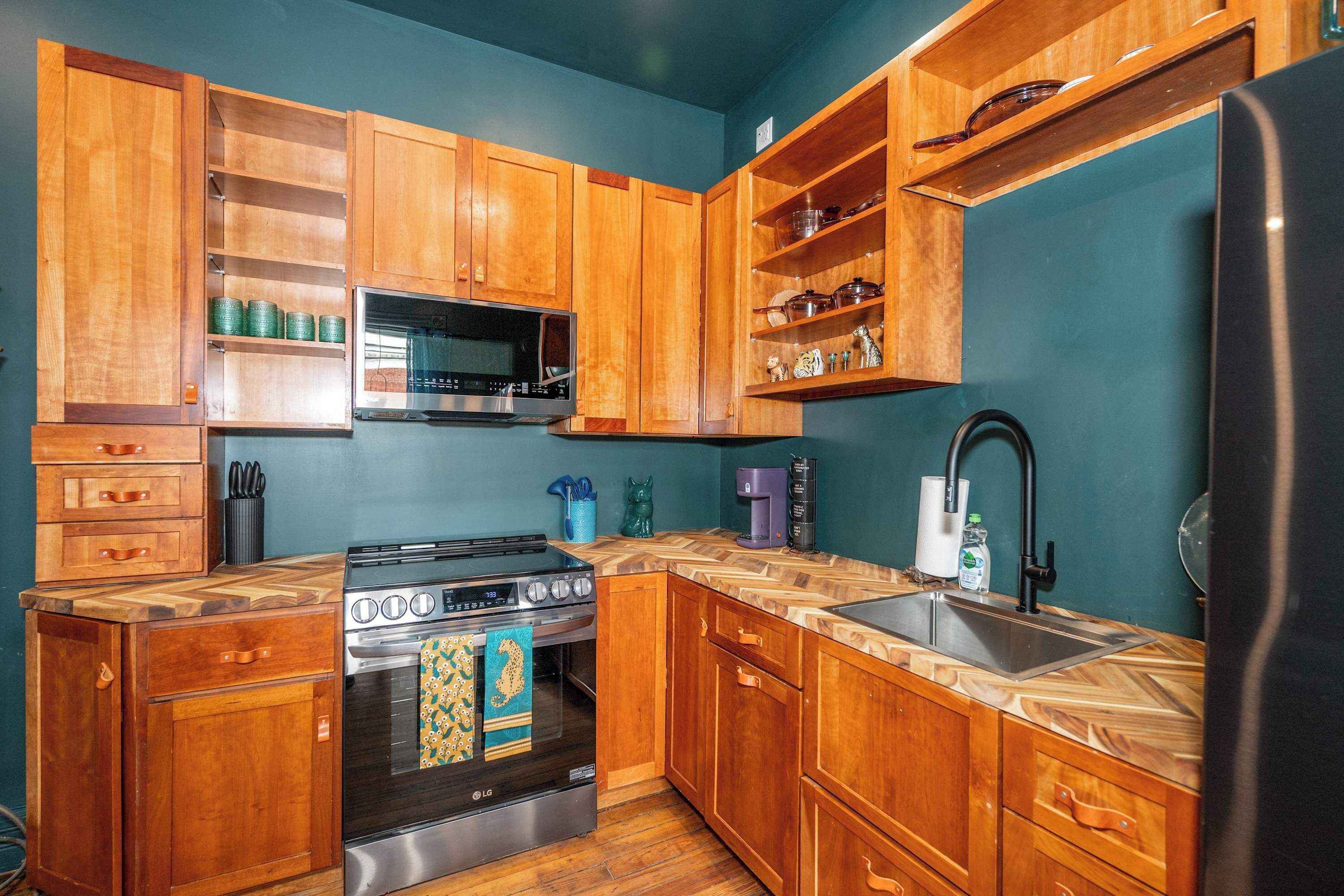A kitchen with wooden cabinets, a stainless steel stove, a microwave, and a refrigerator.