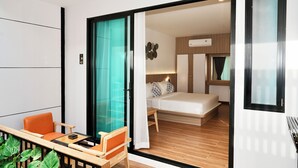 Une chambre d’hôtel moderne avec un balcon, un lit et un petit coin salon.