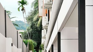 Un étroit sentier dallé, bordé de plantes verdoyantes, et un escalier menant à un bâtiment.