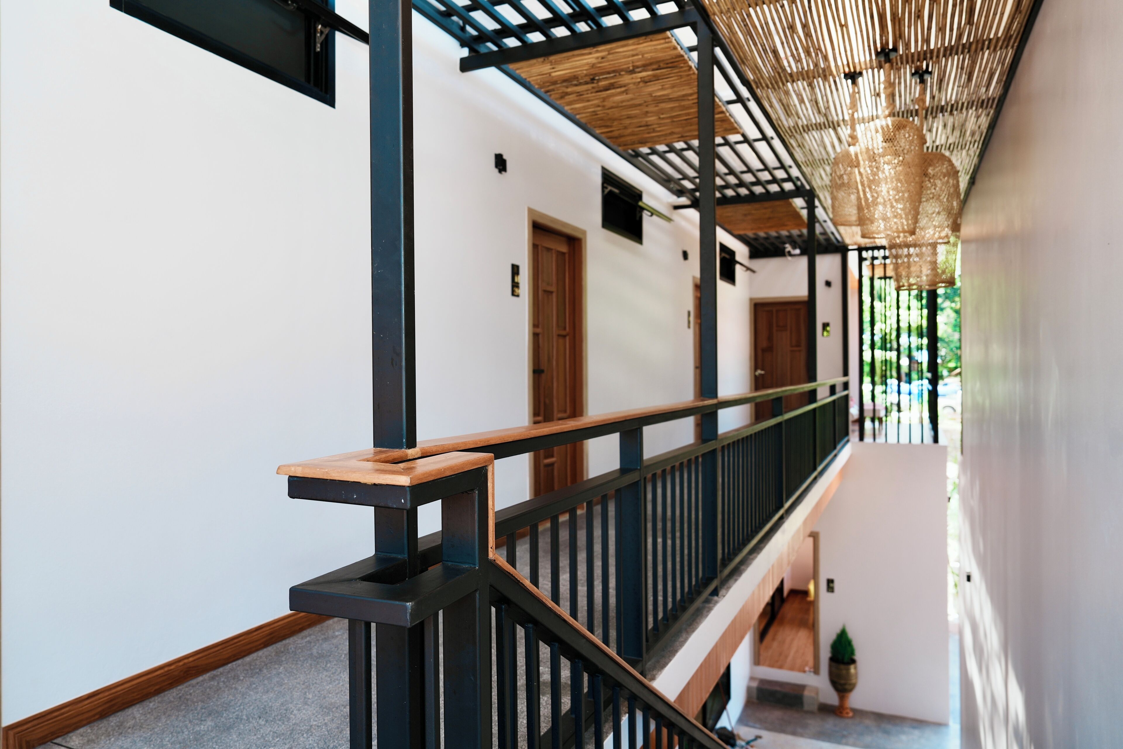 A modern interior with a wooden staircase, black railings, and a bamboo ceiling.