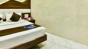 A modern hotel room with a large bed, a wooden headboard, a nightstand, and a wall-mounted clock. - Hotel Palace Residency (Mumbai)