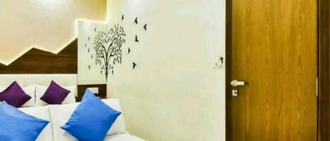 Habitación de hotel con cama, puerta de madera y decoración de un árbol con pájaros.
