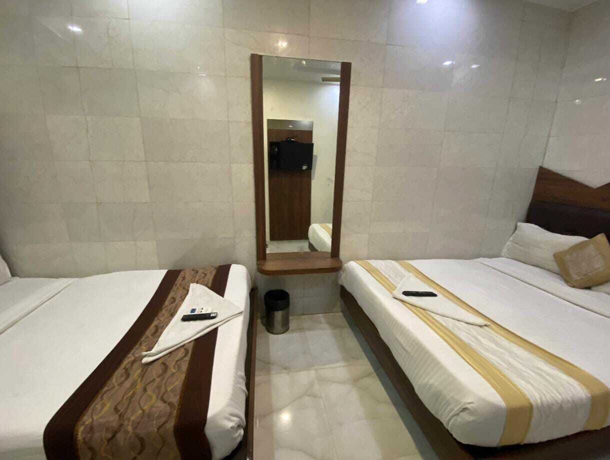 Una camera d'albergo con due letti singoli, uno specchio e un cestino.