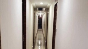 A long, narrow hallway with a shiny floor and white walls. - Hotel Palace Residency (Mumbai)