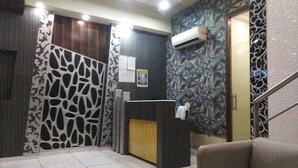 A reception area with a reception desk, a staircase, and patterned walls. - Hotel Palace Residency (Mumbai)