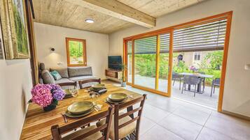 A dining area with a wooden table set for four, a sofa, and a TV in the background.