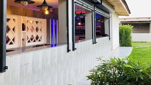 Un bar moderno con interior de madera, amplios ventanales y lámparas colgantes.