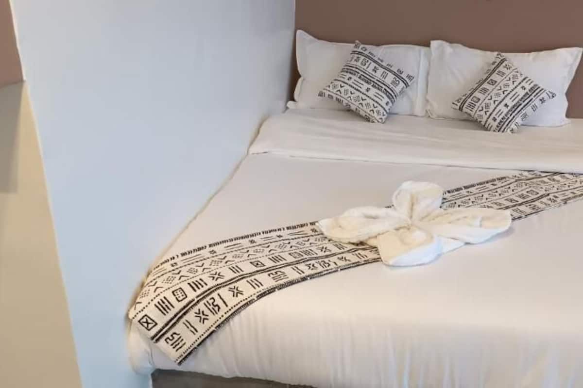 A neatly made bed with a patterned blanket and a towel.