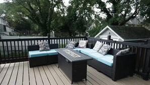 A deck with a black outdoor sofa set, a coffee table, and a small table with decorative items.