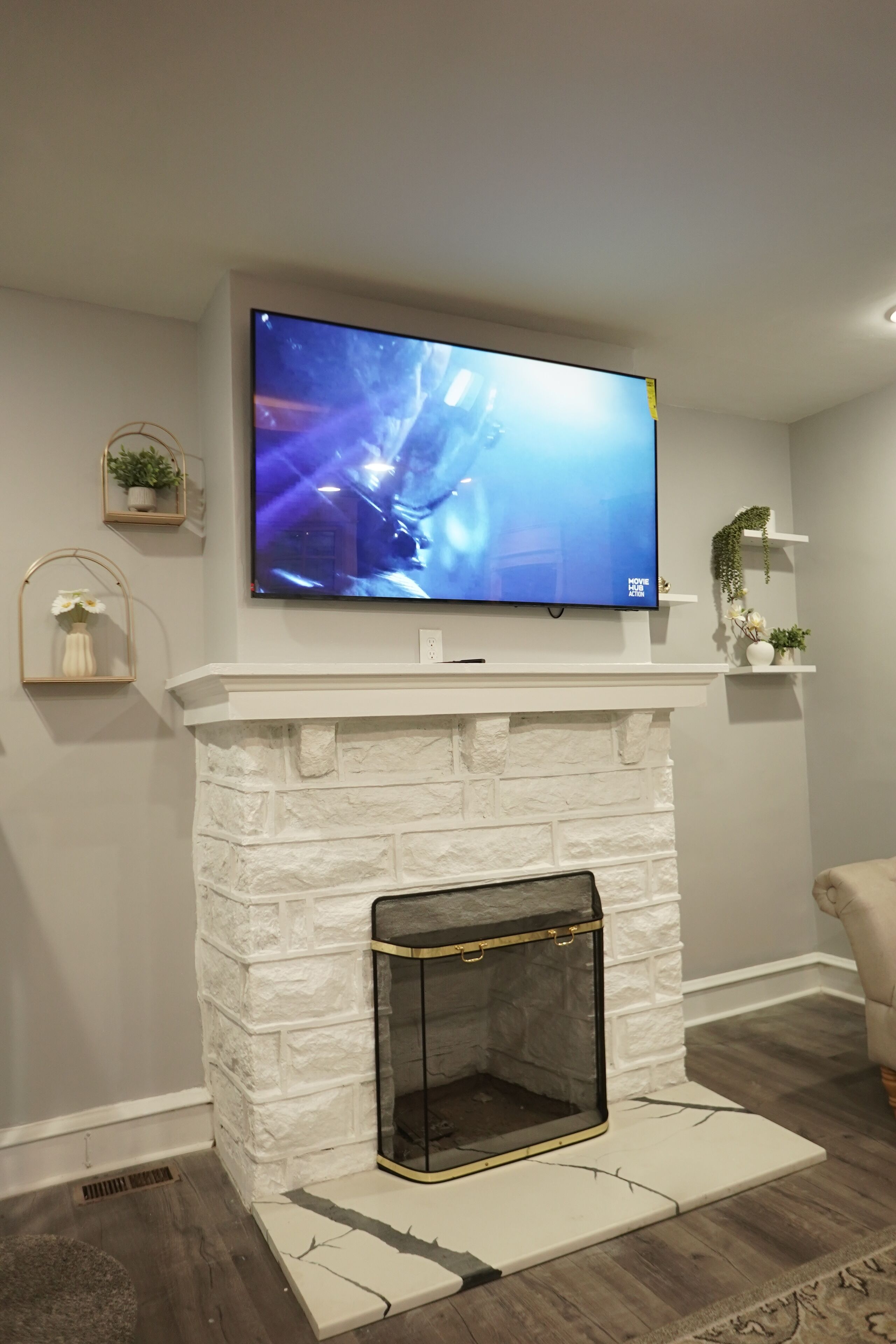 A modern living room with a white stone fireplace, a mounted flat-screen TV, and a minimalist decor.