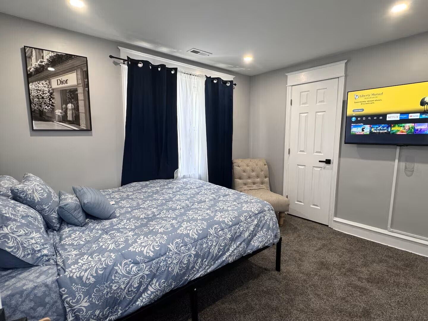 A bedroom with a bed, a chair, a TV, and a door.