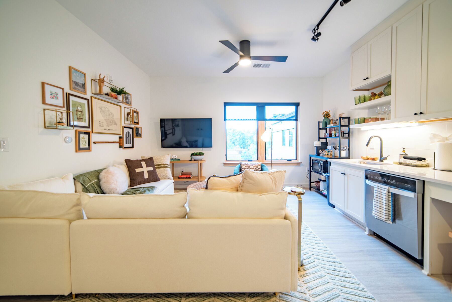 A modern living room with a sofa, a flat-screen TV, and a dining area with a kitchen.