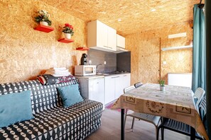 Ein gemütlicher Raum mit Sofa, Esstisch, Küchenzeile und Holzwänden.