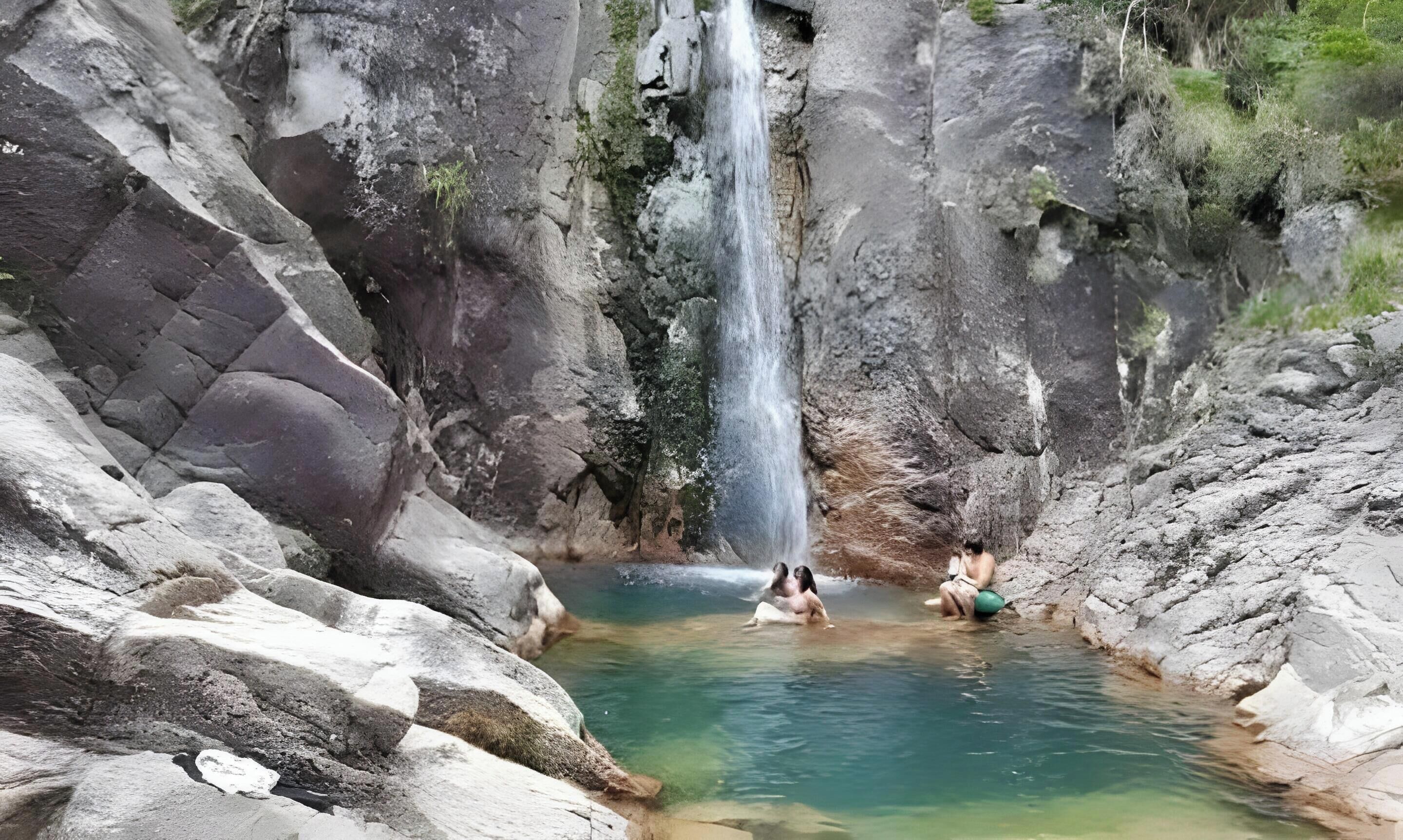 Eine natürliche Felsformation mit Wasserfall und einem Wasserbecken.