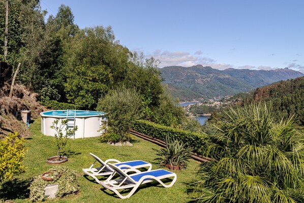A pool with lounge chairs, surrounded by greenery and mountains in the background.
