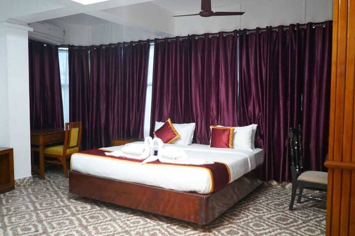 A hotel room with a large bed, a wooden nightstand, a chair, and a desk.