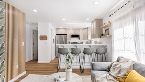A modern kitchen with a central island, bar stools, and a dining area. - Modern 2BR Gem , Near UW & Lake Trails & Garage (Seattle)