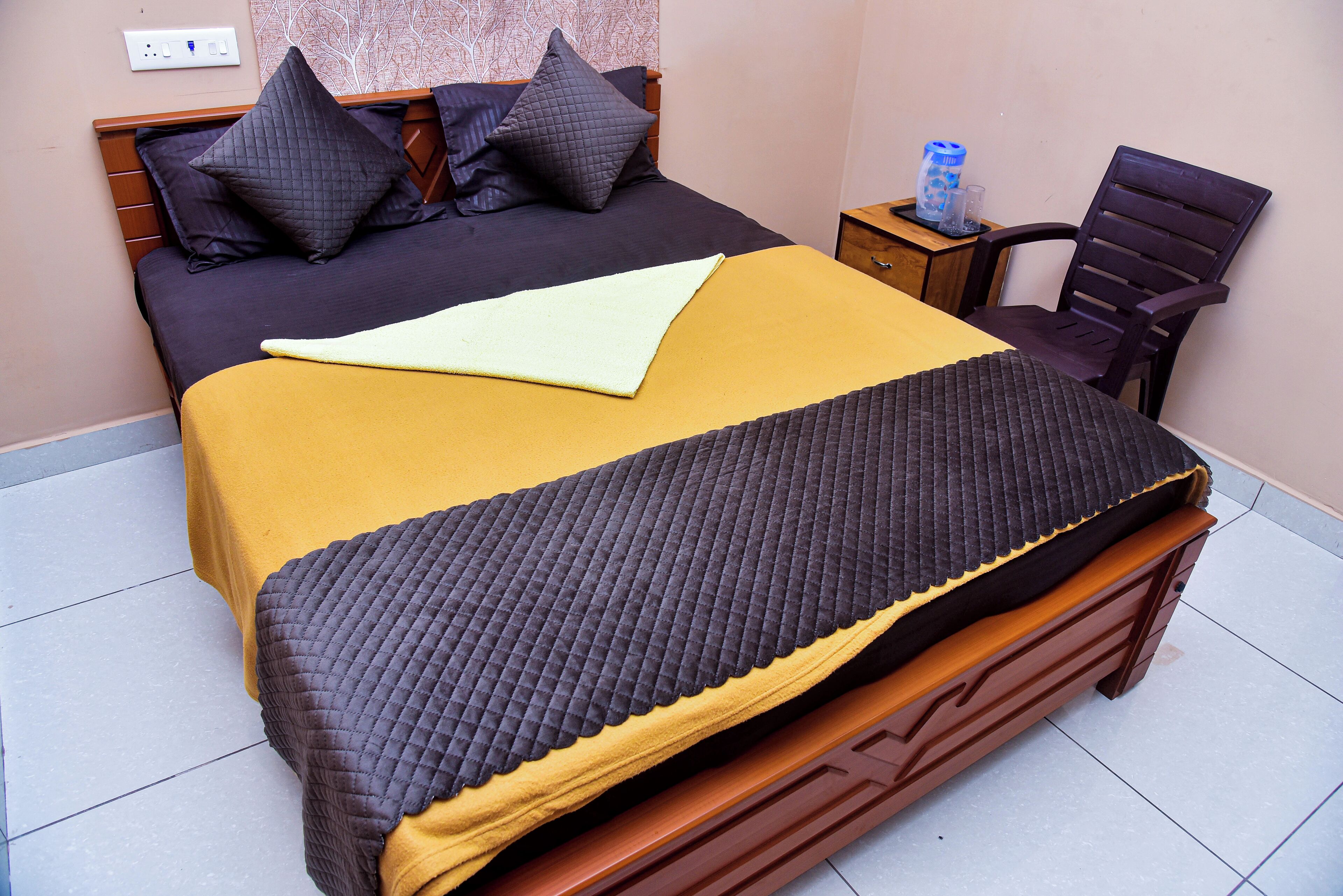 A neatly made bed with a yellow and brown bedspread, a wooden headboard, and two pillows.