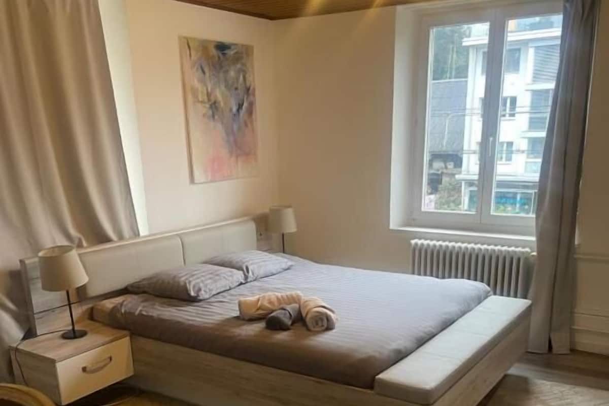 Une chambre à coucher avec un lit, des tables de chevet, un bureau et une fenêtre.